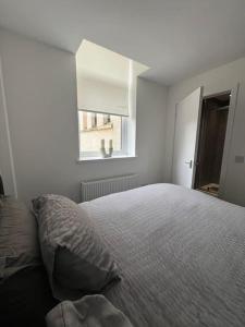 a white bedroom with a bed and a window at The M Rooms in Kirk of Shotts