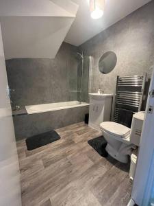 a bathroom with a toilet and a bath tub at The M Rooms in Kirk of Shotts