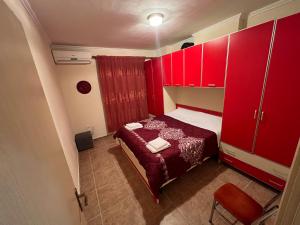 um pequeno quarto com armários vermelhos e uma cama em Anisa appartament em Durrës