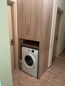 uma máquina de lavar e secar roupa debaixo de um armário de madeira em Anisa appartament em Durrës
