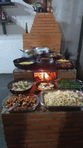 a buffet with many different types of food and a fire at Pousada Mirante Santo Antônio in Rio Prêto