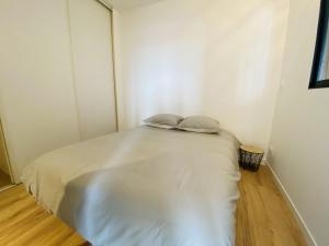 um pequeno quarto com uma cama branca e 2 almofadas em Le Soulicou em Rodez