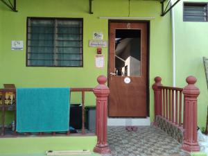 a green house with a wooden door and a balcony at Putat Gajah Villa PASIR MAS in Pasir Mas