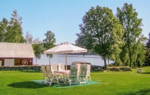 a table and chairs under an umbrella in a yard at Gorgeous Home In Lnsboda With Lake View in Lönsboda