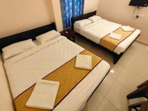 2 Betten in einem Hotelzimmer mit Handtüchern darauf in der Unterkunft LE TOWNSHIP RESIDENCY in Puducherry