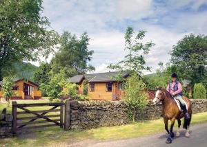 a woman riding a horse in front of a house at Angecroft Park in Ettrick