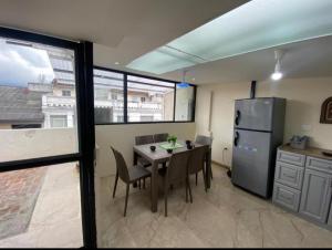 eine Küche mit einem Tisch mit Stühlen und einem Kühlschrank in der Unterkunft Departamento Enorme en Condominio Privado del Centro Histórico. Ecualodge 29 in Cuenca