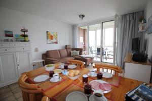 uma sala de estar com uma mesa de madeira com cadeiras e uma cozinha em Horizont-Wohnung-3 em Cuxhaven