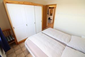 um quarto com uma cama branca e armários brancos em Horizont-Wohnung-3 em Cuxhaven
