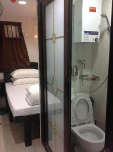 a small bathroom with a toilet and a bed at Payless Guest House A2 in Hong Kong