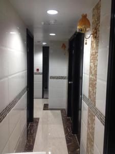 baño con puertas negras y paredes de azulejos blancos en Payless Guest House A2, en Hong Kong