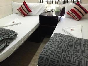 two beds in a room with a phone on a table at Payless Guest House A2 in Hong Kong