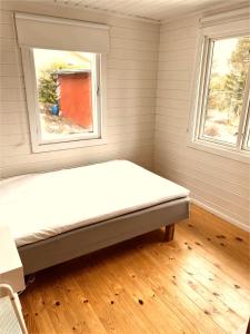 Bett in einem Zimmer mit 2 Fenstern in der Unterkunft Värmdö in Värmdö
