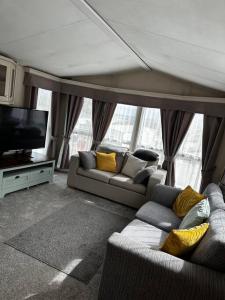 a living room with two couches and a flat screen tv at 2 bedroom caravan, sea views, parking in Eastchurch