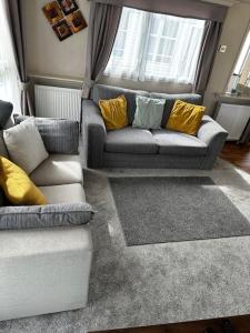a living room with two couches and yellow pillows at 2 bedroom caravan, sea views, parking in Eastchurch