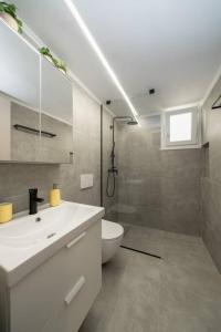La salle de bains est pourvue d'un lavabo blanc et de toilettes. dans l'établissement 'Santa Marina Detached Cozy House In Egaleo, à Athènes