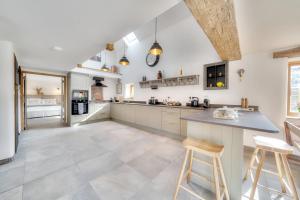a large kitchen with a counter and stools at Tumbledown Barn in Knowstone