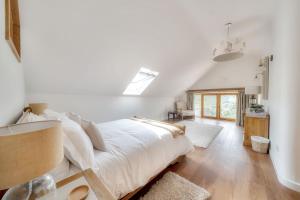 um quarto com uma cama grande e lençóis brancos em Tumbledown Barn em Knowstone
