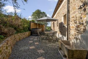 a patio with a table and an umbrella at Tumbledown Barn in Knowstone