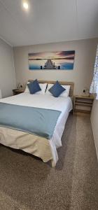 a bedroom with a large white bed with blue pillows at Beautiful Caravan With Decking Wifi At Isle Of Wight, Sleeps 4 Ref 84047sv in Porchfield