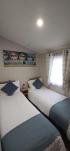 two beds in a small room with a window at Beautiful Caravan With Decking Wifi At Isle Of Wight, Sleeps 4 Ref 84047sv in Porchfield