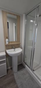 y baño con lavabo blanco y ducha. en Beautiful Caravan With Decking Wifi At Isle Of Wight, Sleeps 4 Ref 84047sv en Porchfield