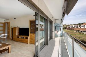 einen Balkon mit Glastüren und einem TV darauf in der Unterkunft Modern and renewed Apartament Florí in Arenys de Mar