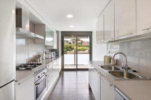 eine weiße Küche mit einer Spüle und einem Herd in der Unterkunft Modern and renewed Apartament Florí in Arenys de Mar
