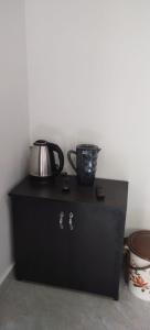 a black cabinet with a tea kettle on top of it at Katakeri Deluxe Holiday Homes in Madikeri