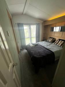 a bedroom with a large bed with a window at 2 bedroom caravan, sea views, parking in Eastchurch