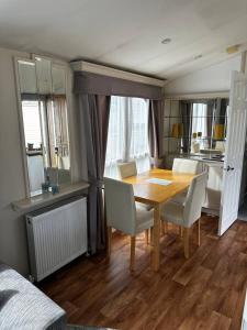 een eetkamer met een houten tafel en stoelen bij 2 bedroom caravan, sea views, parking in Eastchurch