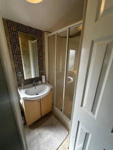 La salle de bains est pourvue d'un lavabo et d'une douche. dans l'établissement 2 bedroom caravan, sea views, parking, à Eastchurch