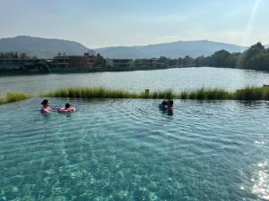 a group of people swimming in a lake at Khaoyai Kirimaya Atta Residence 5 BR Villa in Ban Tha Chang