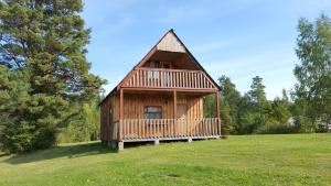 eine große Holzhütte auf einer Wiese in der Unterkunft Priedīši in Aglona