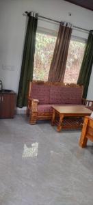 a living room with a couch and a table at Katakeri Deluxe Holiday Homes in Madikeri