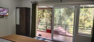 a bedroom with a window with a view of a porch at Katakeri Deluxe Holiday Homes in Madikeri