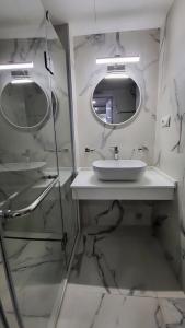 a white bathroom with a sink and two mirrors at Alliance Palace Batumi in Batumi