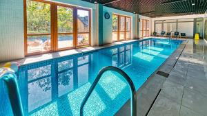 una gran piscina de agua azul en un edificio en Apartament A12 Green Resort z Basenem, Sauną, Jacuzzi - 5D Apartments, en Szklarska Poręba