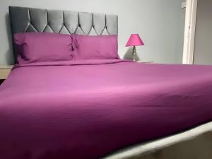 a purple bed with a purple bedspread and a pink lamp at Central Reading 2 Wash Rooms FREE PARKING in Reading