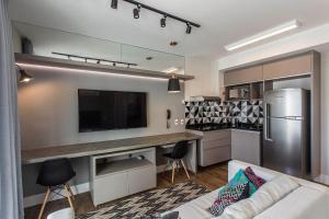 a living room with a couch and a tv and a kitchen at ADD Berrini in Sao Paulo
