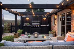 un patio al aire libre con parrilla y mesa en The Blended Barn, en Stratford-upon-Avon