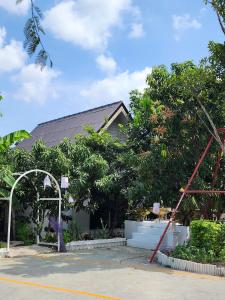 una casa con árboles delante de ella en สวนชะลอม, en Ban Ton Chuak