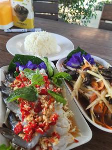 tres platos de comida en una mesa con arroz en สวนชะลอม en Ban Ton Chuak