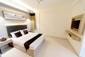 a hotel room with a bed and a television at Super Collection O Metro Park Opposite Kalasipalya Bus stand in Bangalore