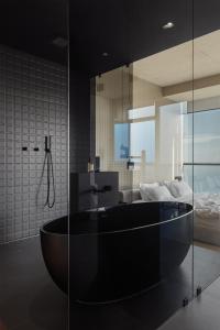 a bathroom with a black tub and a bedroom at Sea and Sky Apartment in Odesa