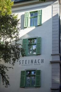 a white building with green shutters on it at Steinach Townhouse Meran in Merano