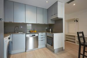 una cocina con armarios blancos y electrodomésticos de acero inoxidable en Three bedroom Two bathroom apartment Close to Beach en Barcelona