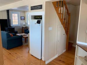 a white refrigerator in a living room with a blue couch at Beautiful oceanfront cottage in Guysborough