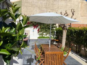 una mesa de madera con una sombrilla en el patio en Conteamare, en Marina di Modica