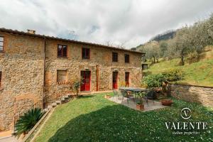 a stone house with a table in a yard at Casa con vista panoramica, Matraia, Lucca in Matraia